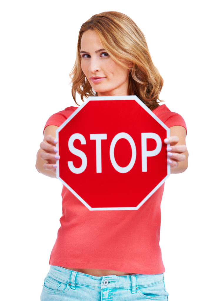 Stop. A young woman holding a stop sign against a white background
