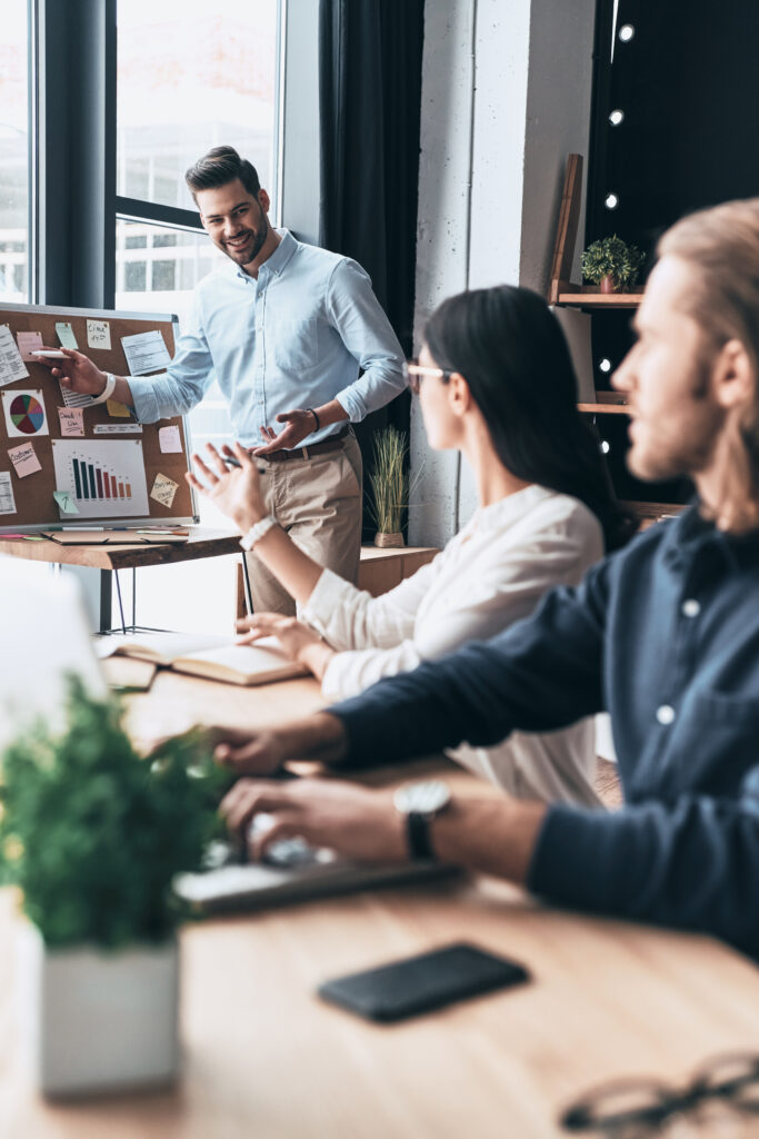 Taking important decision. Group of young business people using blackboard with adhesive notes while working in the office